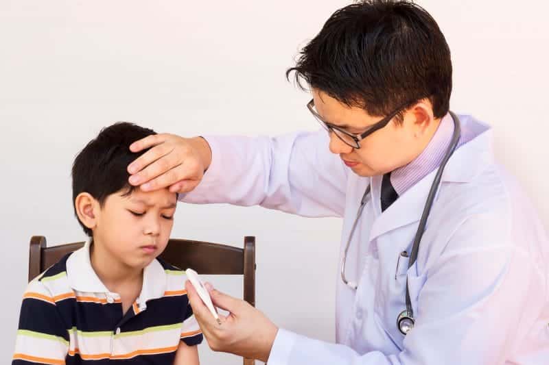 sick asian boy being examined by male doctor white background
