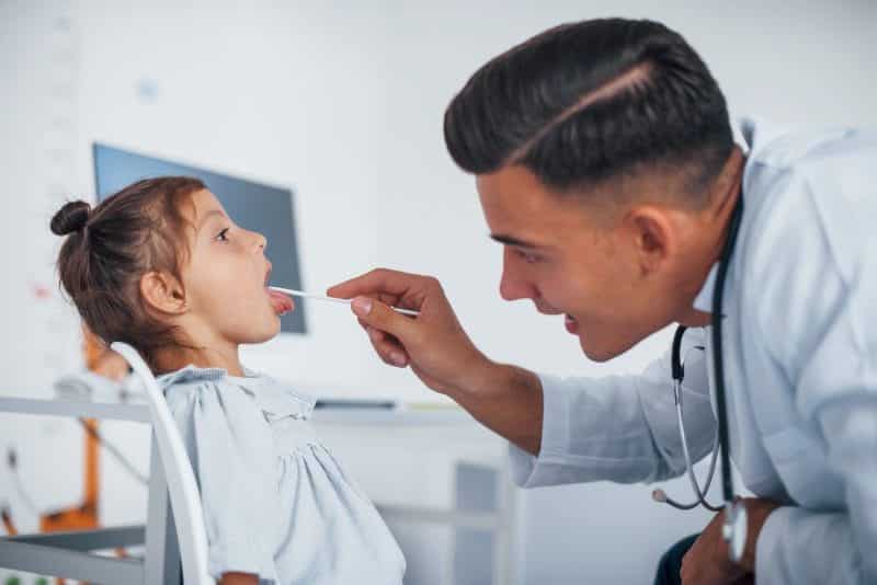 uses tonsil check throat young pediatrician works with little female visitor clinic