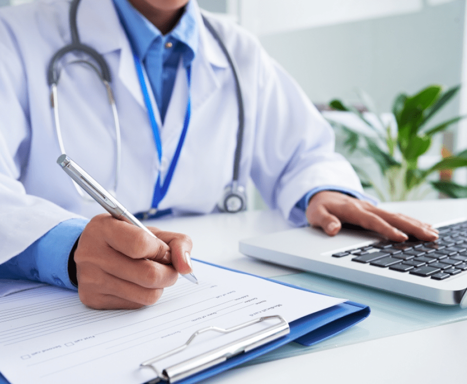 hands unrecognizable female doctor writing form typing laptop keyboard